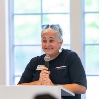 Susan Proctor smiles as she hold microphone in Alumni House